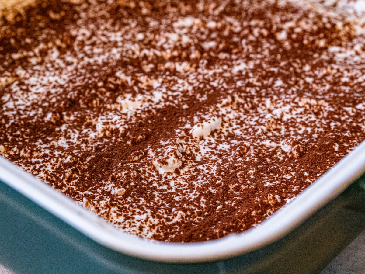 A square slice of tiramisu baked oats showing a dense espresso-cocoa oat base layered with a creamy white yogurt topping and a dust of cocoa powder.